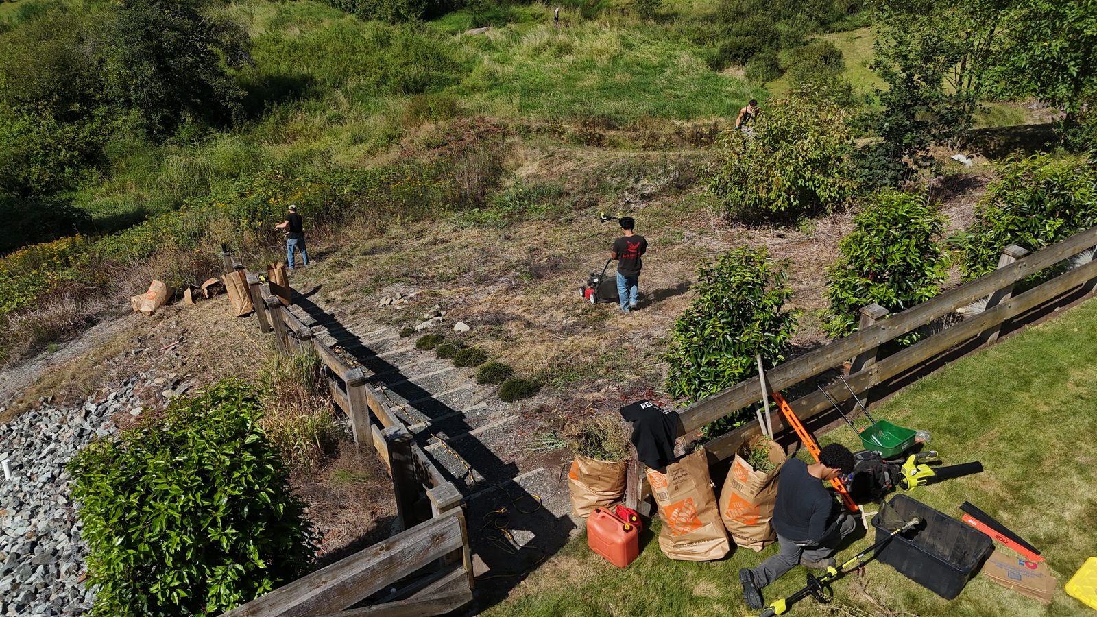 Aerial view of the ZeroWaste crew clearing an overgrown slope — mowing, strimming and trimming, with green waste bagged ready for removal