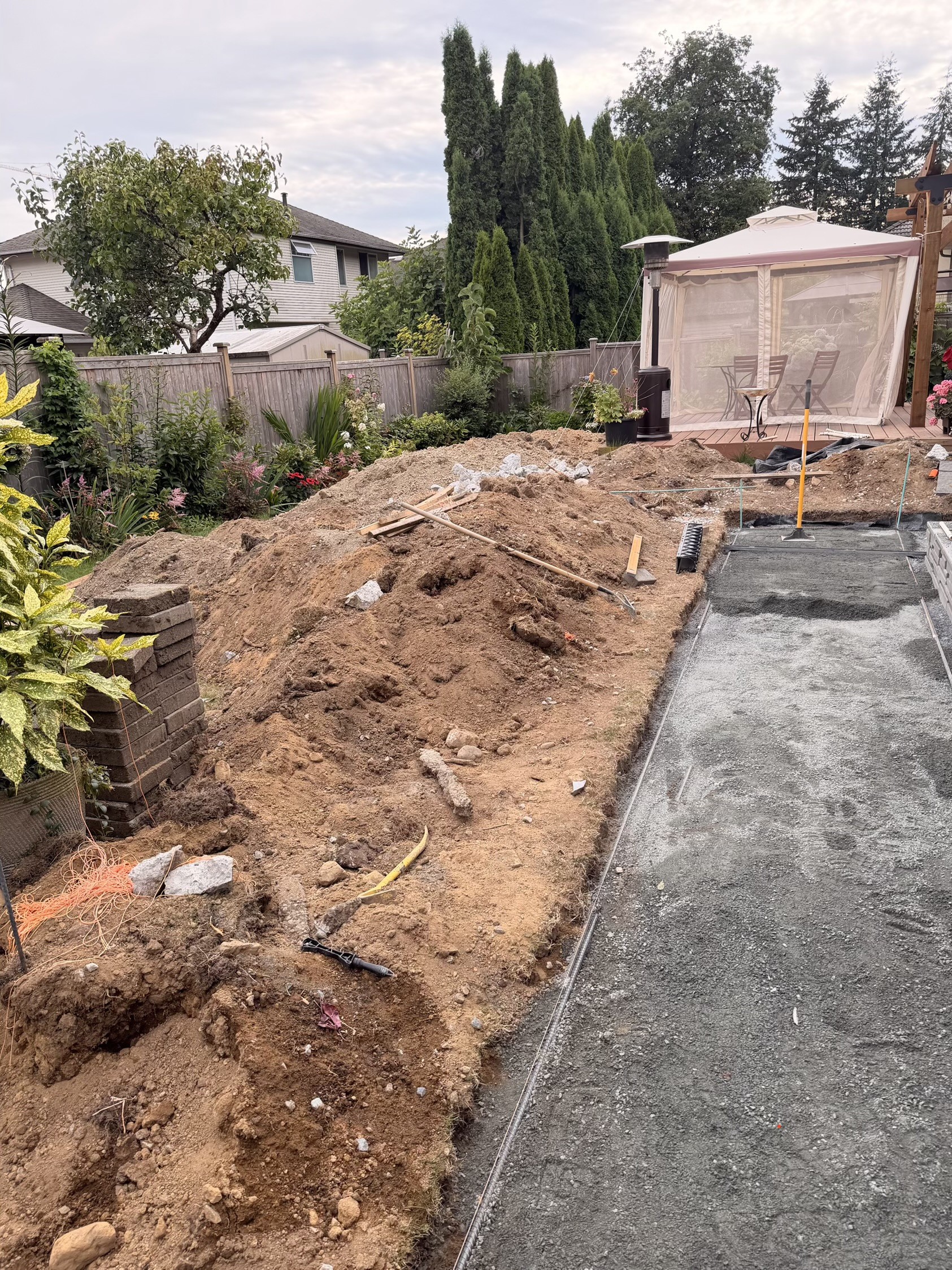 Side yard dug out to bare dirt with a raw gravel base ready for pavers