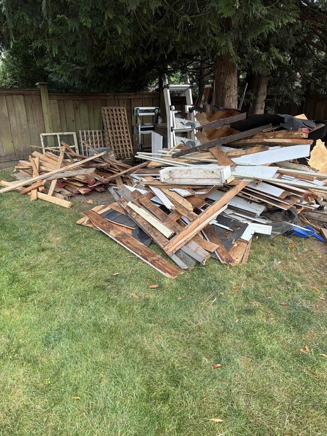 Lumber and building debris stacked across the yard on a separate clear-out