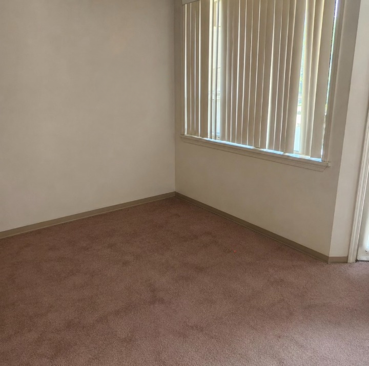 Same bedroom cleared down to bare carpet after mattress and furniture removal